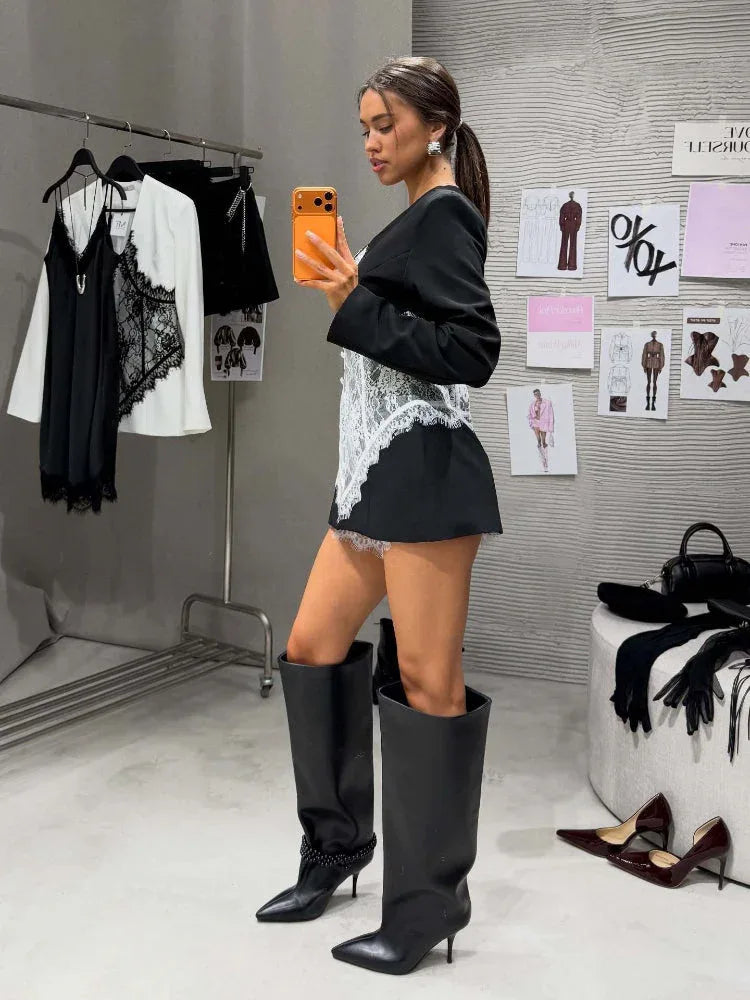 Woman in a black blazer dress with a white lace corset overlay, showcasing the structured shoulders