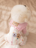 Back view of a white dog in a pink and striped pet jumpsuit with a bear applique and paw print label.
