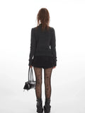 Back view of a woman wearing a dark grey knit cardigan.
