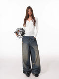Woman holding a soccer ball in a net bag, wearing a white long-sleeve henley shirt and distressed wide-leg jeans