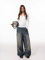 Woman holding a soccer ball in a net bag, wearing a white long-sleeve henley shirt and distressed wide-leg jeans