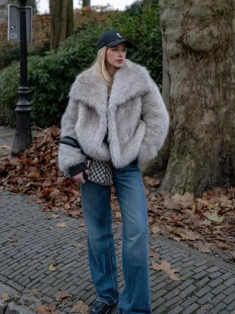 woman wearing a light grey faux fur jacket with a wide collar and black baseball cap