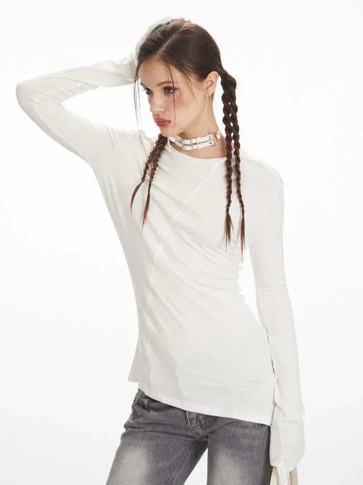 Model posing in a white long sleeve top with asymmetrical seam detail.