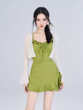 Woman wearing a green textured knit mini dress with ruffled trim and tie-front detail, paired with a white open-knit cardigan with flared sleeves.