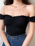 Detail of the ruffled off-the-shoulder neckline on a black top