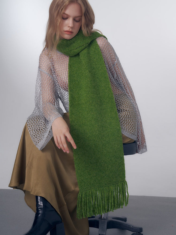 Woman wearing a green knit scarf with fringe details