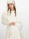 Close-up of a woman's torso wearing a cream knit turtleneck sweater with puffed sleeves and a cream knit mini skirt with a drawstring waist.
