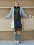 Woman posing with a long, oversized plaid scarf in a studio setting.