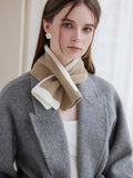 Close-up of a woman's neck and shoulders wearing a beige and white striped knit scarf