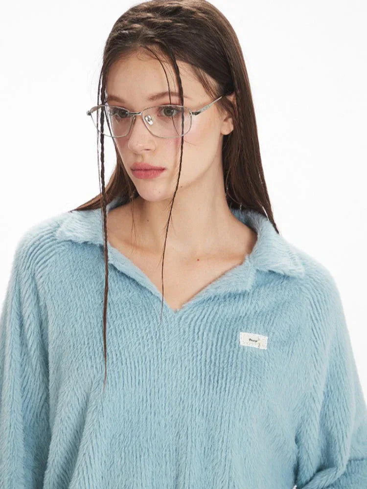 Close-up profile of a model wearing a light blue fuzzy knit collared v-neck sweater, highlighting the collar detail and textured fabric.