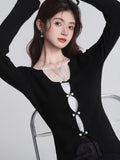 Woman posing with arms raised wearing a black knit top