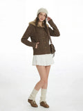 Full body shot of a woman in a brown cardigan, white skirt, and leg warmers.