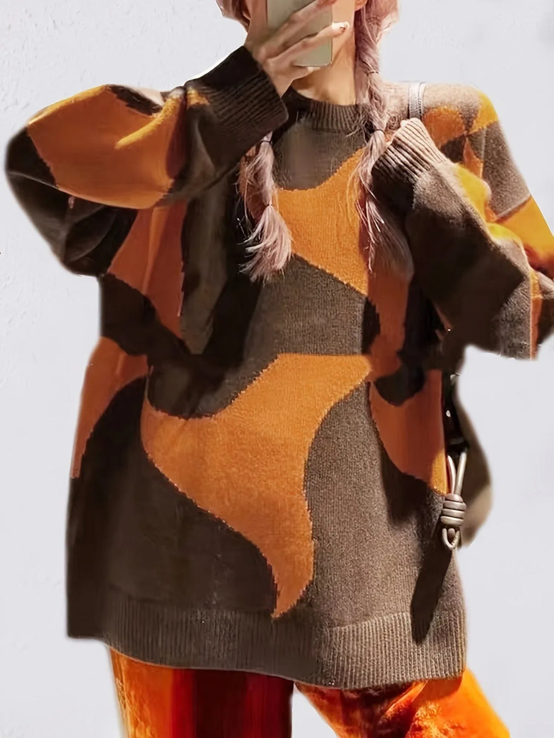 Woman wearing a brown and orange abstract patterned knit sweater with brown shorts and knee-high boots.