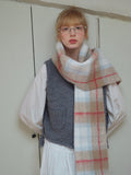 Close-up of a model wearing a plaid scarf with fringe trim.