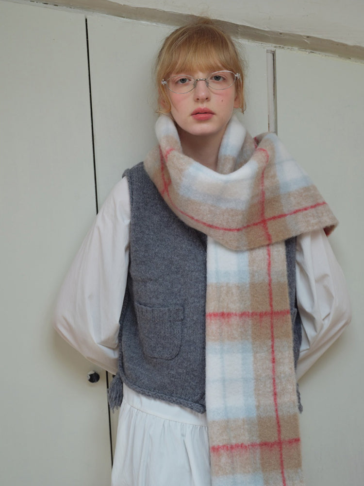 Close-up of a model wearing a plaid scarf with fringe trim.