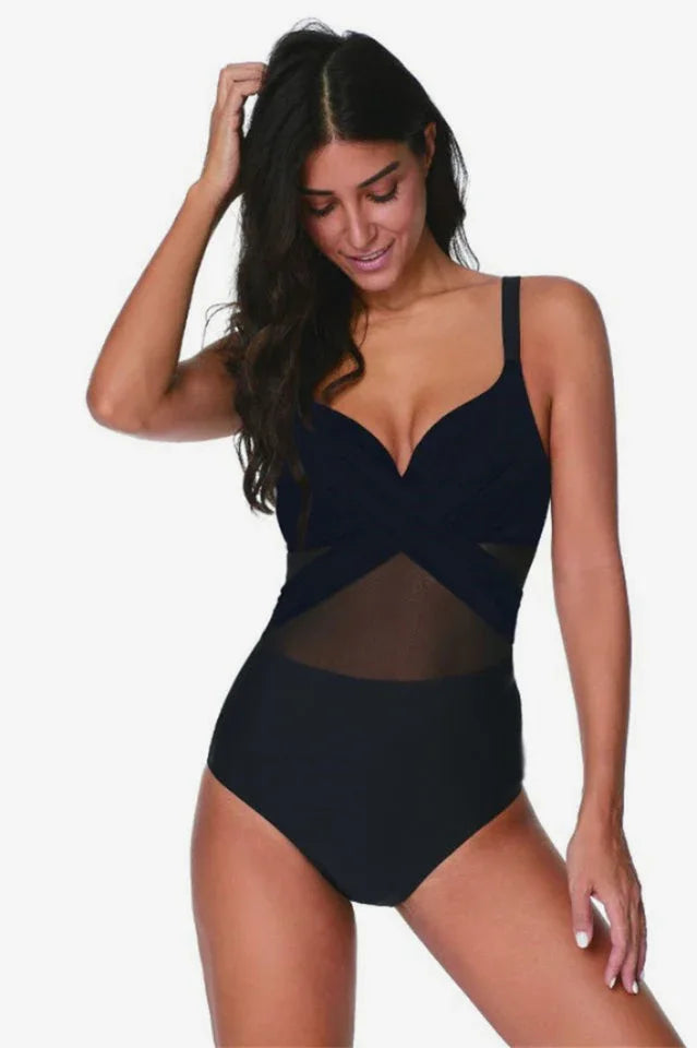 Woman wearing a black one-piece swimsuit with mesh accents and a criss-cross neckline