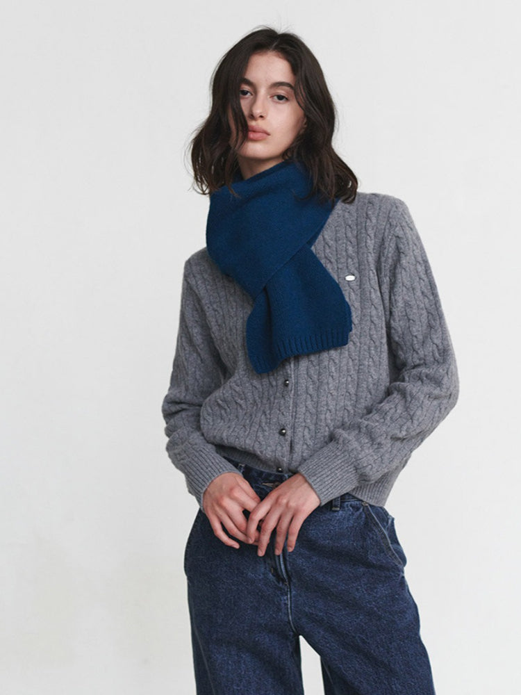 Woman wearing a blue knit scarf and a grey cable knit cardigan
