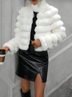 Woman holding a coffee cup while wearing a white faux fur jacket