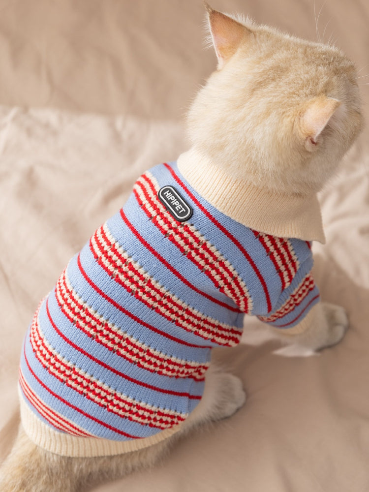 Back view of a cat wearing a blue and red striped knit sweater with a cream collar and HIPPIPET logo patch.