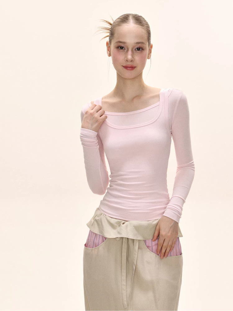 Side profile of a model wearing a light pink long-sleeve fitted top.