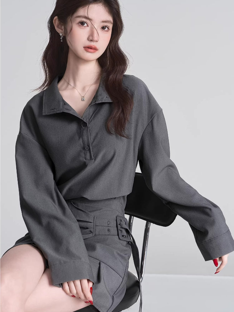 Woman wearing a grey long-sleeve collared shirt and a grey asymmetrical skirt