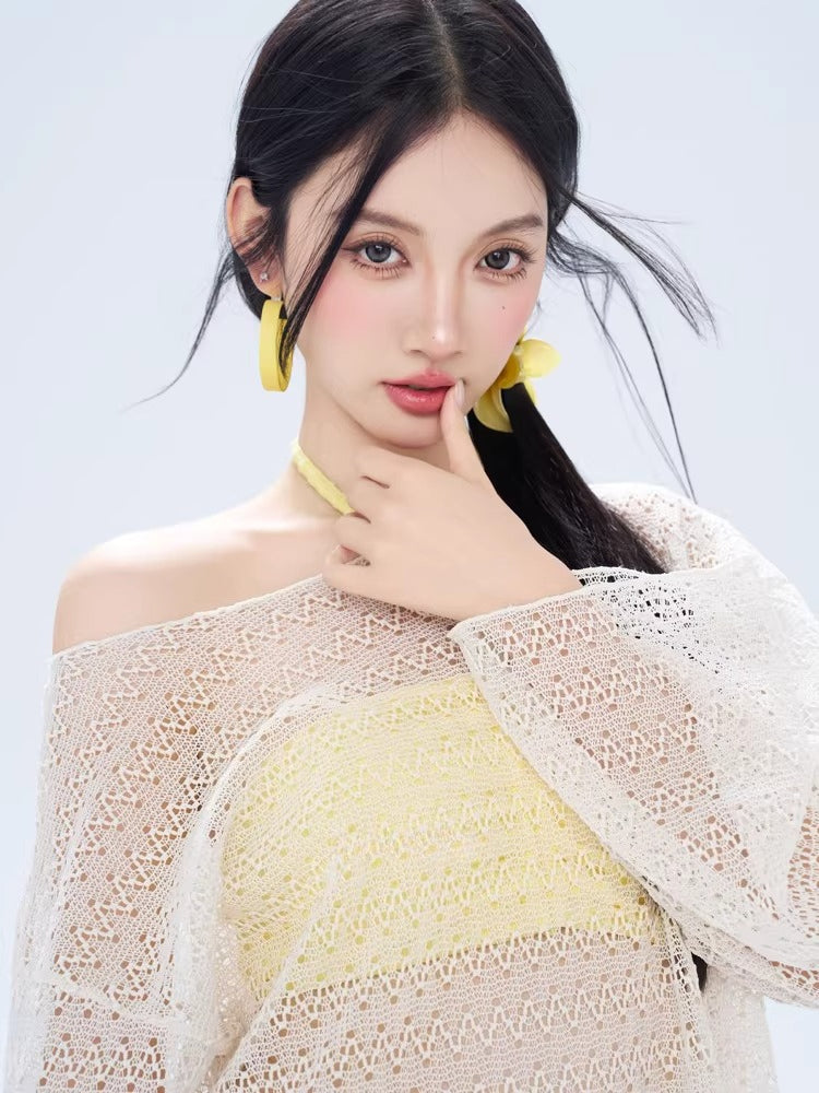 Model wearing a white open knit off-the-shoulder cover-up over a yellow halter bikini set.