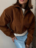 Woman wearing a brown corduroy cropped bomber jacket with a full zip front and classic collar.