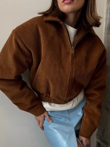 Woman wearing a brown corduroy cropped bomber jacket with a full zip front and classic collar.