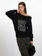 Side profile of a woman showcasing the off-the-shoulder design of a black knit sweater with faux fur trim and a graphic print.