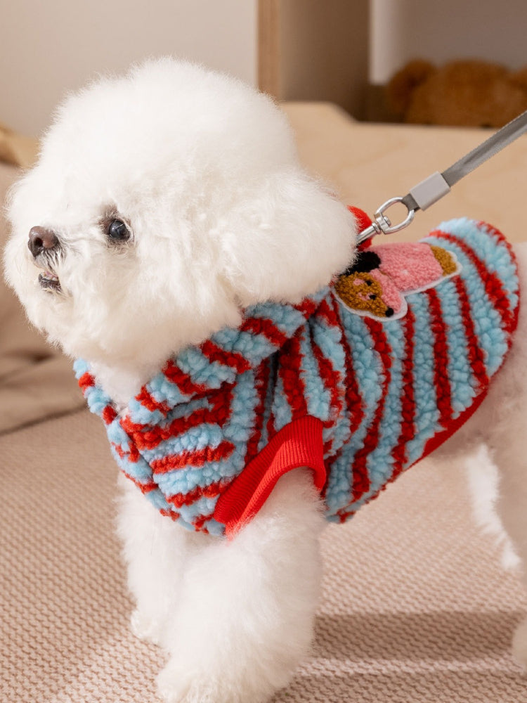 Side view of a dog wearing a blue and red striped hooded dog coat with red ribbed cuffs.