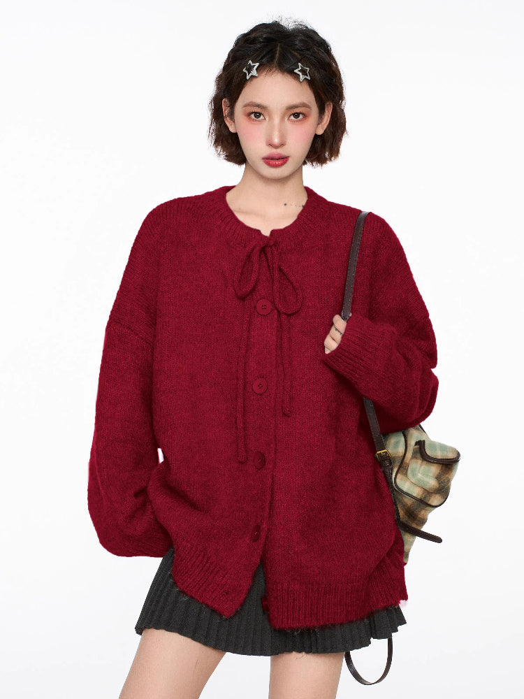Woman wearing a red knit cardigan with a tie closure and button front, paired with a pleated skirt and knee-high socks.