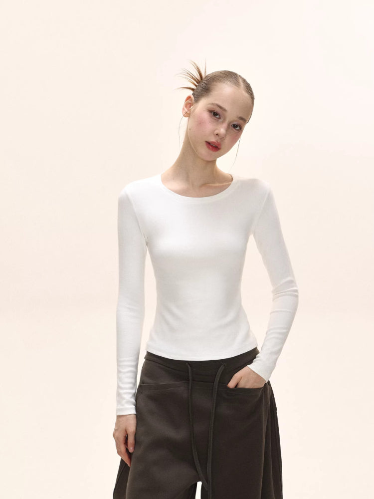 Model wearing a white long-sleeve ribbed knit top with a crew neckline.