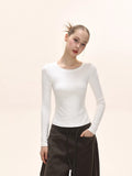 Front view of a woman in a white fitted long-sleeve top.