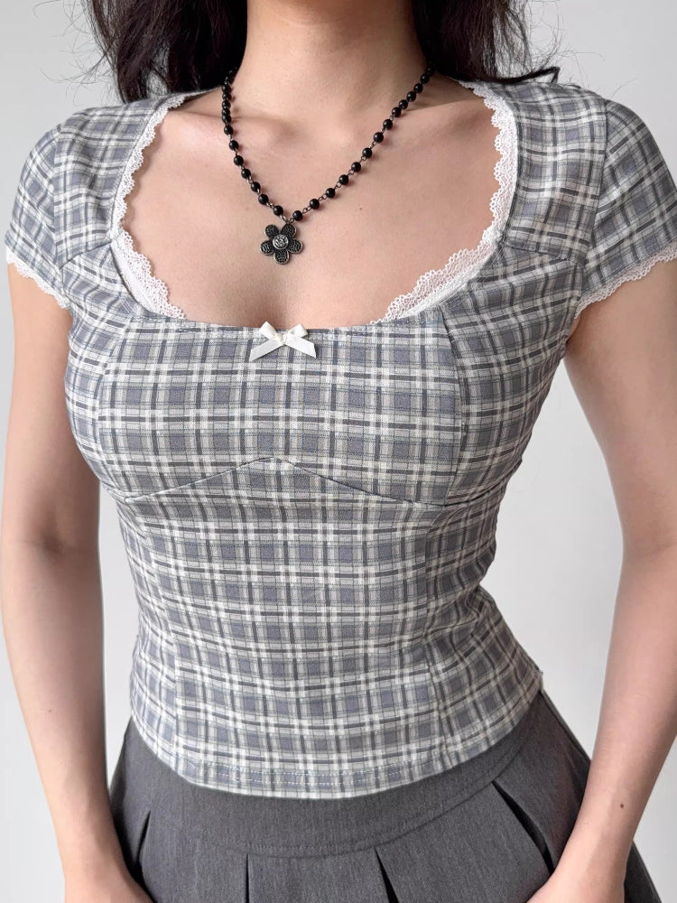 Detailed view of the neckline and chest area of a grey plaid top featuring lace trim and a bow accent.
