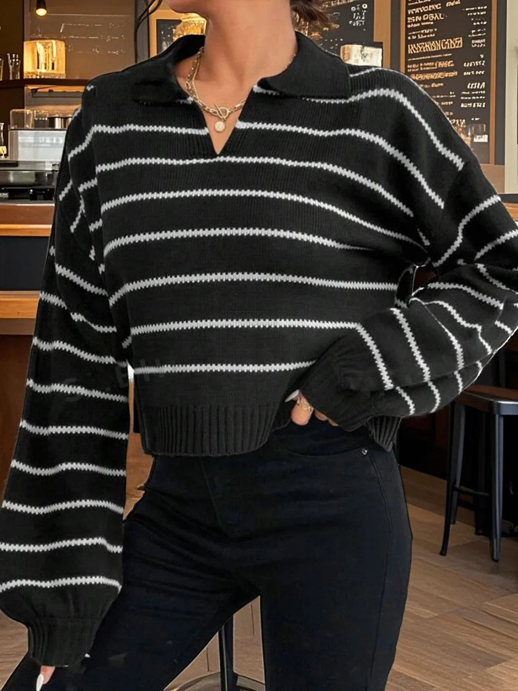 Close-up of a woman's torso showing the detail of a black and white striped cropped knit sweater.