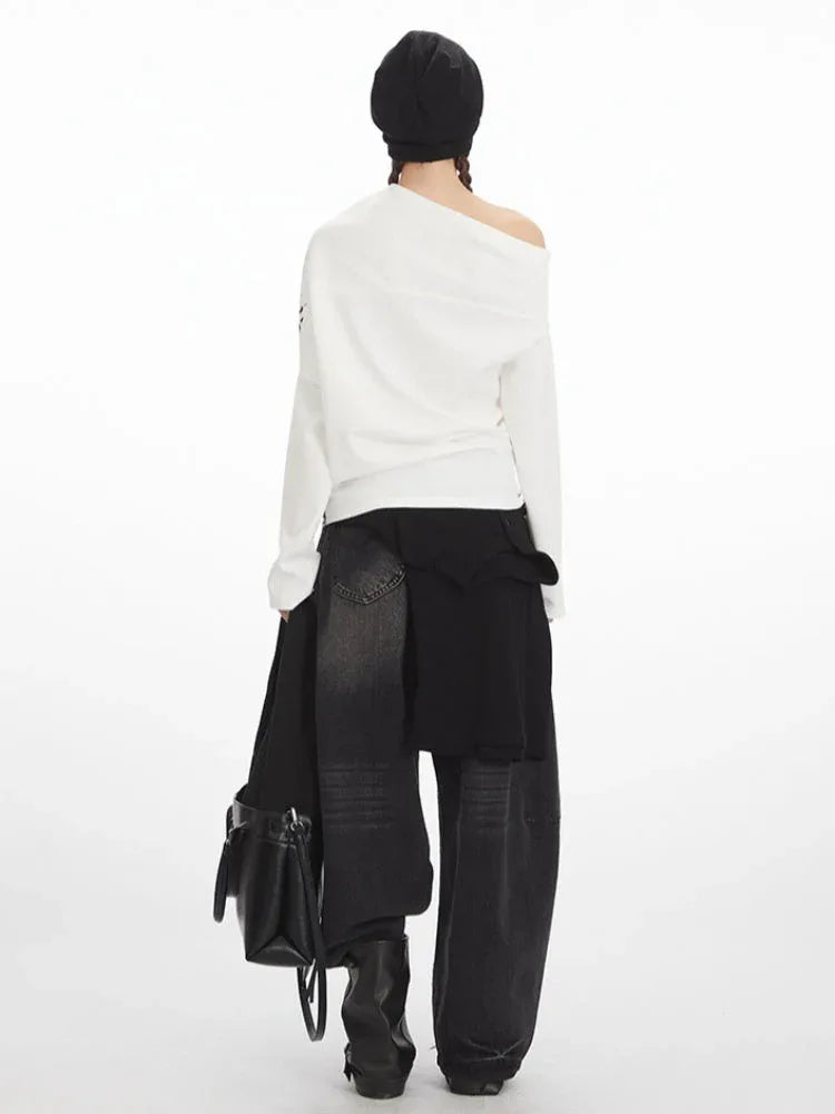 Back view of a woman wearing a white long-sleeve graphic print top with an off-the-shoulder design and black jeans.