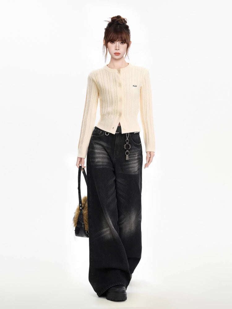 Woman modeling a cream cable knit cropped cardigan, dark wash wide-leg jeans, and a handbag with a faux fur accent.