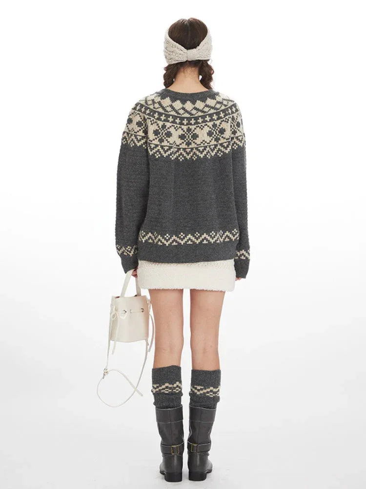 Woman wearing a grey Fair Isle crewneck sweater with a cream beanie and skirt