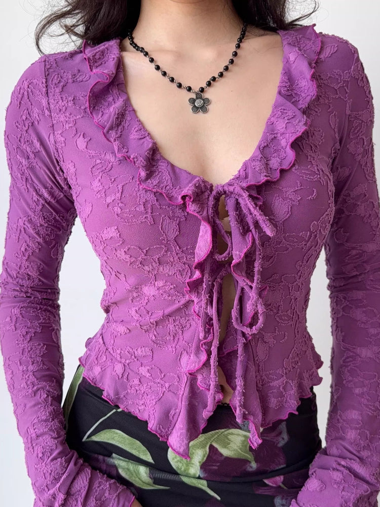 Detail of the neckline and tie closure on a purple textured mesh long-sleeve top.