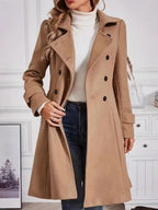 Woman wearing a camel double-breasted wool blend coat, open to show a white turtleneck and blue jeans