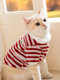 Cat wearing a red and white striped fleece pet jacket with a white collar, looking upwards.