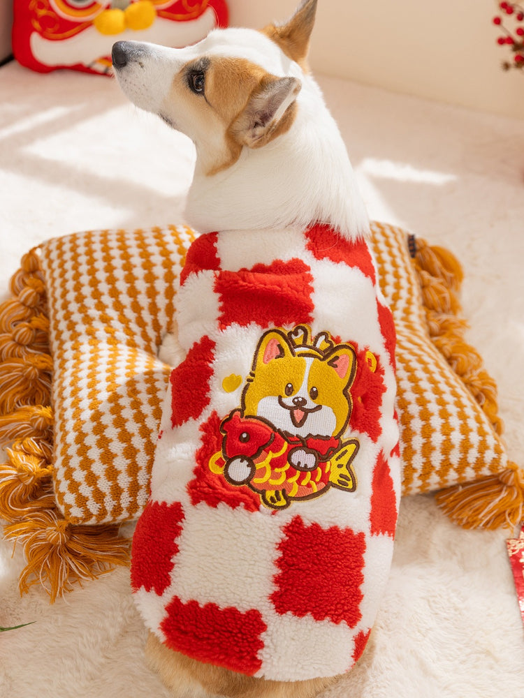 Side view of a corgi dog in a red and white checkerboard plush dog coat with a cartoon character embroidery.