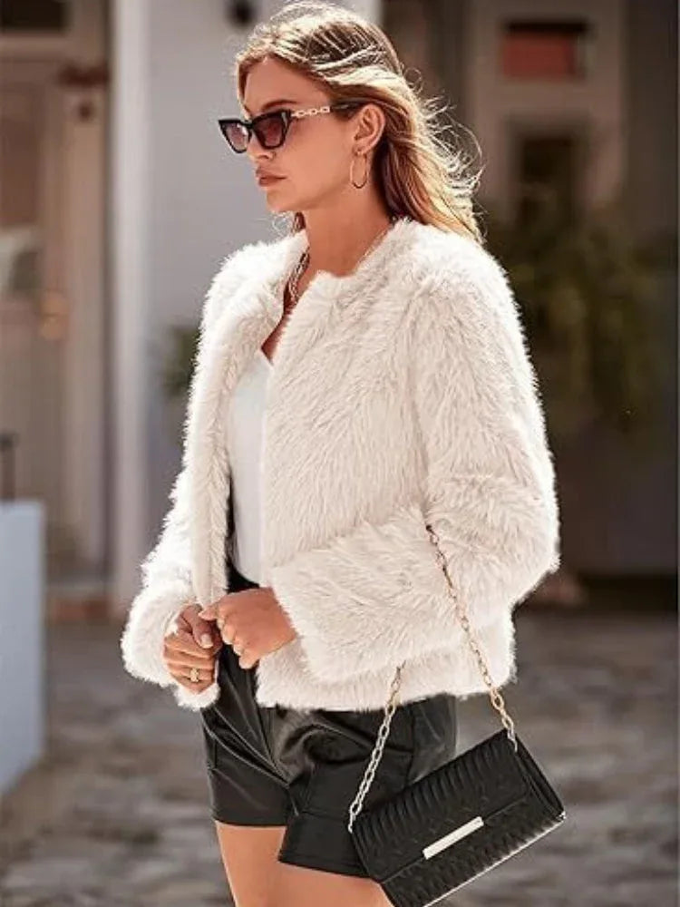 Woman with a handbag wearing a white faux fur cropped jacket and black shorts.