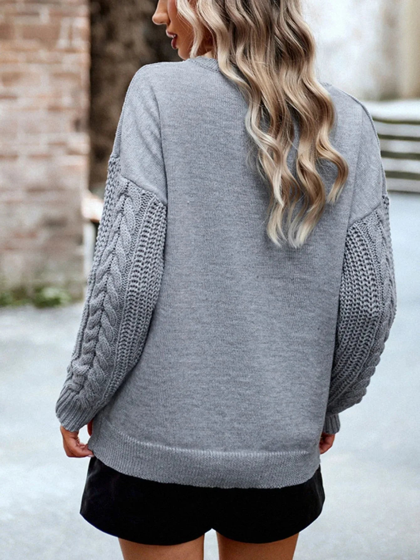 Front view of a woman's outfit featuring a grey sweater and black shorts