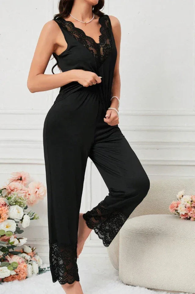 Woman wearing a black sleeveless pajama top and wide-leg pants with lace trim, standing.
