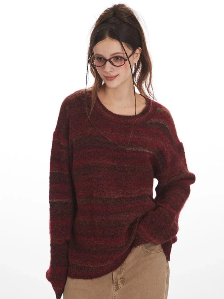 Close-up of a woman wearing a maroon and brown striped oversized knit sweater.