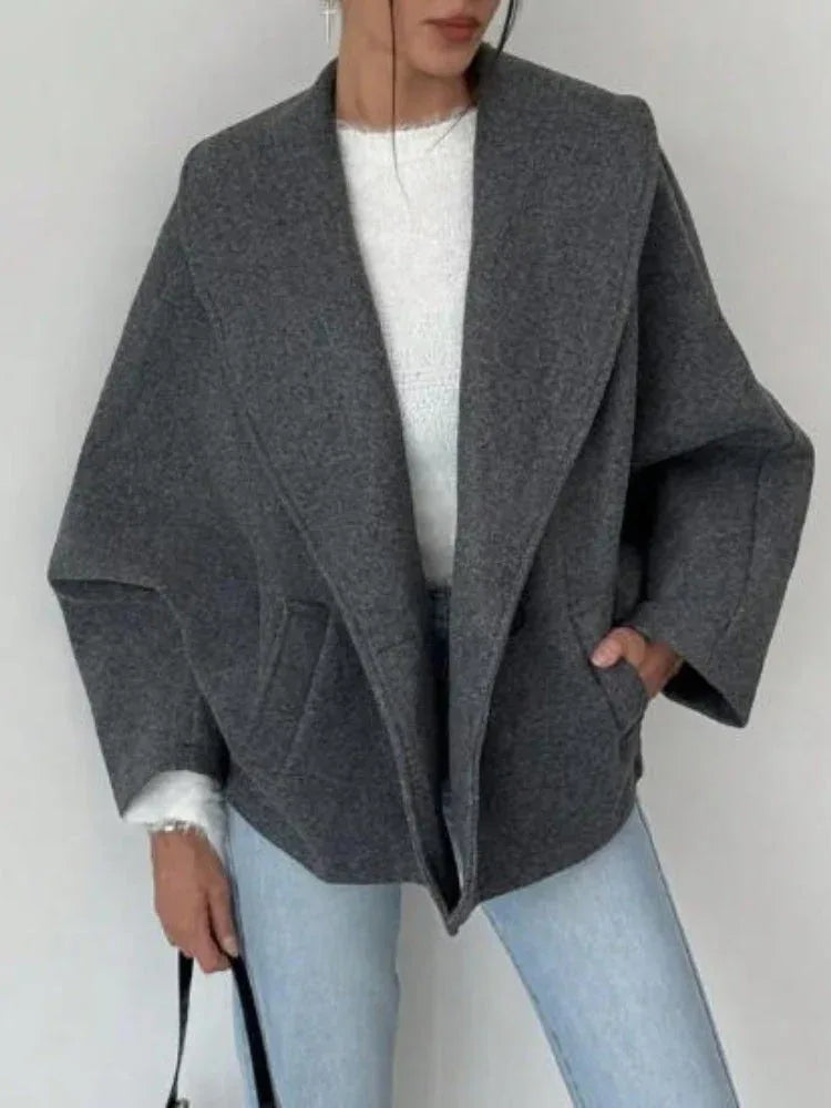 Woman wearing a grey wool blend oversized coat with wide lapel collar and batwing sleeves. Main image