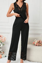 Woman wearing a black sleeveless pajama top and wide-leg pants with lace trim, standing, front view.