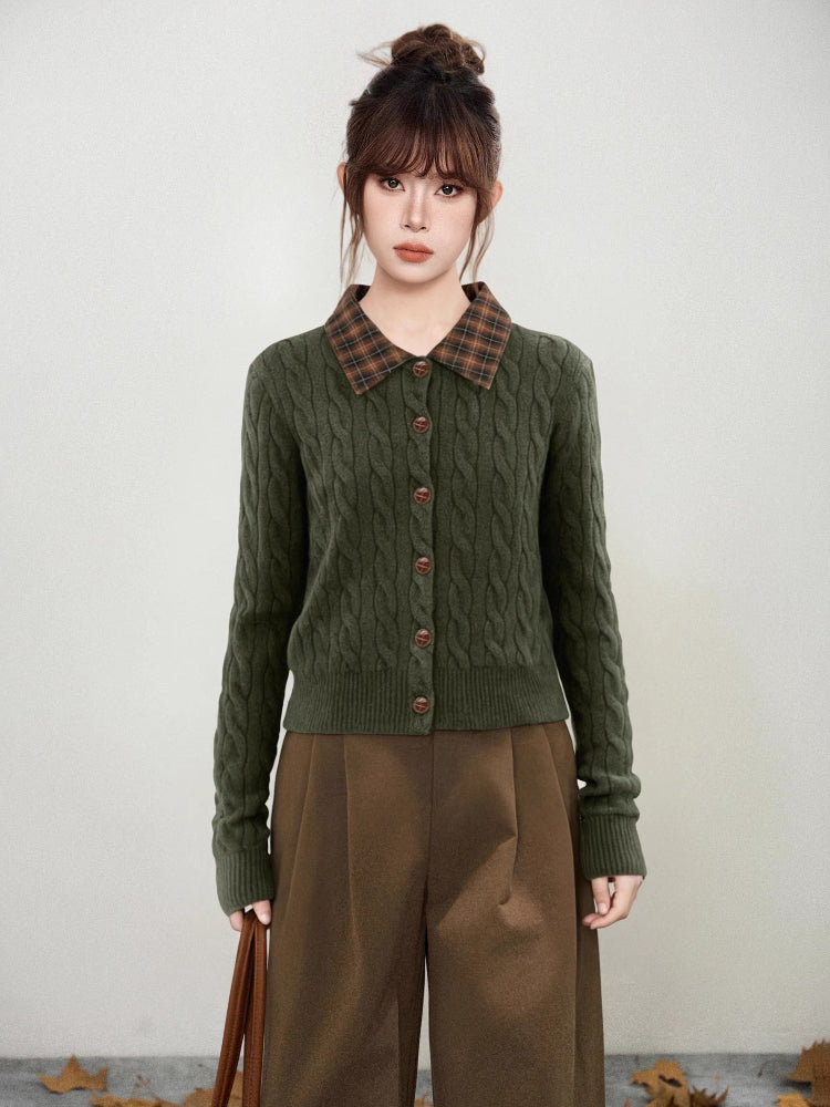 Woman wearing a dark green cable knit cardigan with a brown plaid collar and brown buttons.