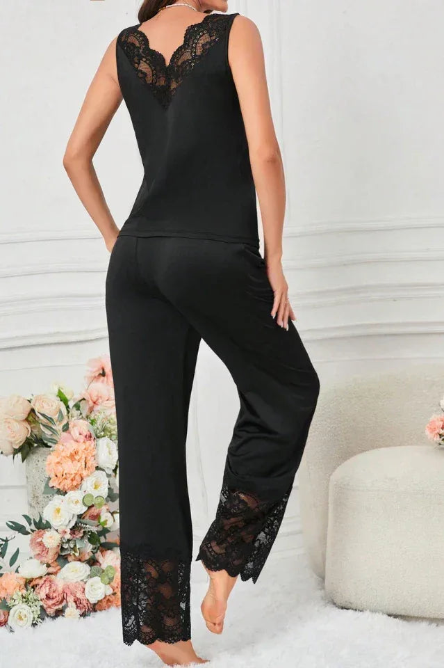 Woman wearing a black sleeveless pajama top and wide-leg pants with lace trim, standing, back view.